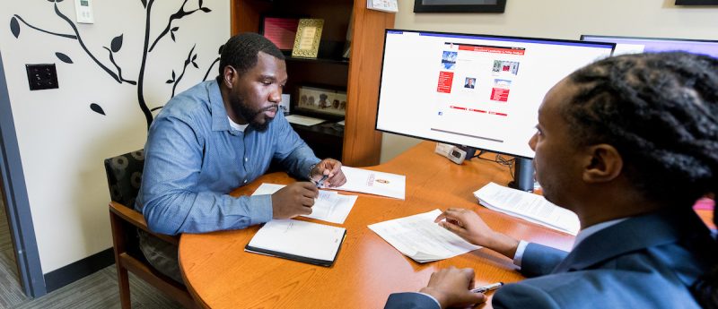 Professor Brian Burt meeting with Blayne Stone, student.