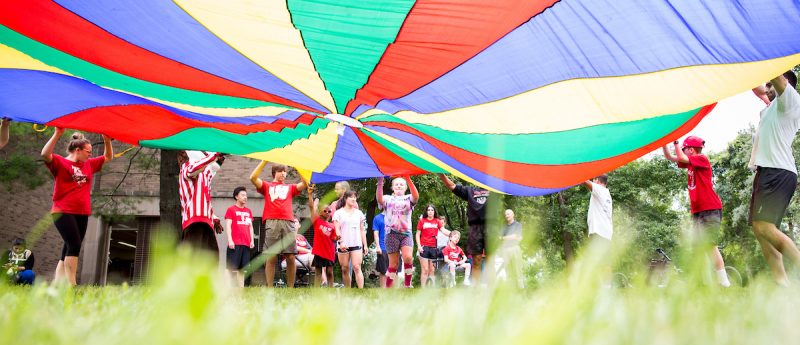 Students playing with a colorful parachute.