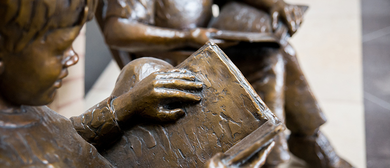 Bronze sculpture depicting children reading books