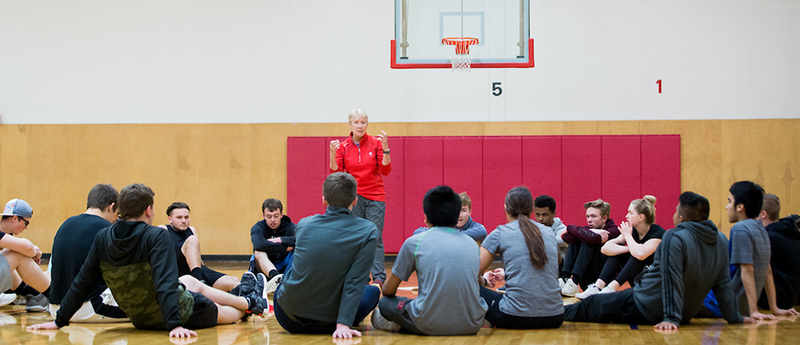 Students seated on basketball court in physical education class