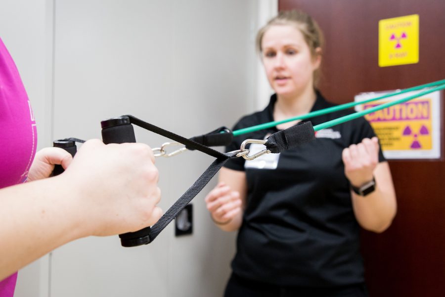 Health care professional coaches woman doing resistance strengthening exercises